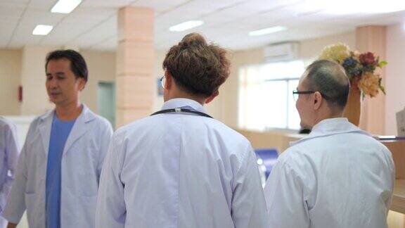 后视图两个严肃的亚洲医生团队走过医院的走廊他们交谈和讨论病人的诊断数据持有数字平板电脑技术