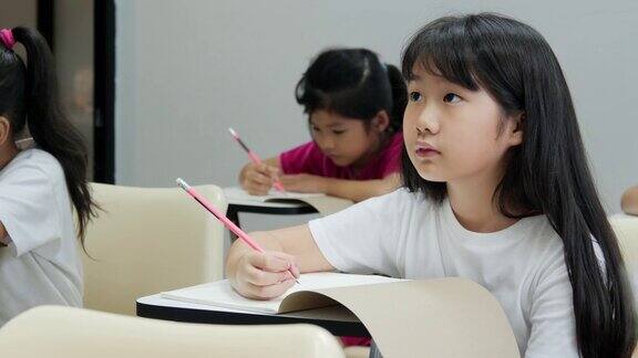 女孩在课堂上认真听老师讲课和写作教育