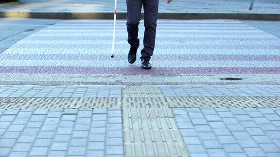 盲人男性用白色手杖过马路用触觉瓷砖导航城市