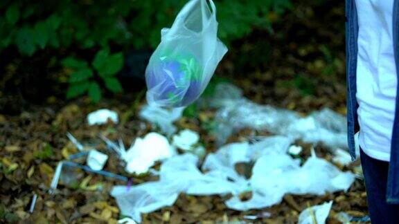 粗心大意的女人把地球玩具装在塑料袋里扔在地上垃圾填埋场回收利用