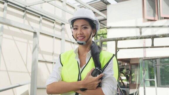 亚洲女工的肖像人们戴着防护安全帽和眼镜现场的建筑女工程师站在那里交叉着胳膊微笑着看着镜头