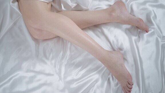 漂亮女人躺在卧室的床上女人的腿上的白床单特写