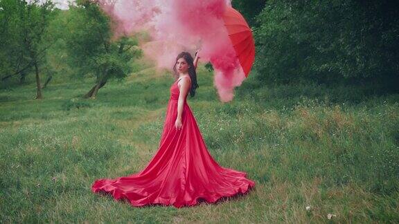 穿着红裙子手里拿着伞的美女女王在森林中拍照