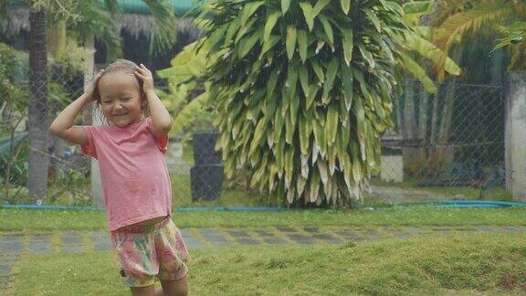 肖像5岁的小女孩在热带雨中玩耍慢镜头