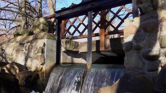 水闸闸门控制齿轮与齿轮运河与瀑布和岩石溪下面在明媚的阳光早晨