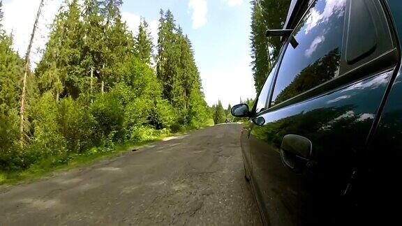 绿色汽车行驶在破旧的乡村道路与木材夏天的时间