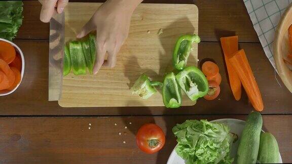 女首席制作沙拉健康食品和切甜椒在厨房的砧板上俯视图