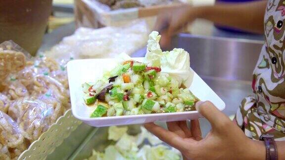 年轻的亚洲女人购买食物木瓜沙拉著名的泰国街头食品或在食品店