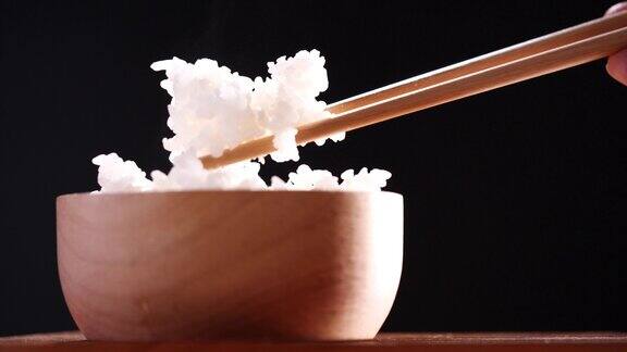 日本米饭煮米饭接近自然蒸熟的日本白米饭木碗与筷子在黑色背景柔软的焦点健康食品