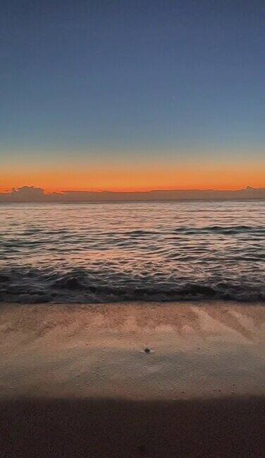 垂直比海水波浪在沙滩上与蓝天在清晨的日出