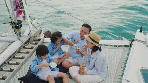 一个亚洲家庭带着两个孩子在游艇上玩得很开心