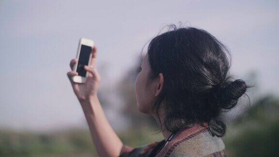 年轻女子早上站在河边用智能手机拍照