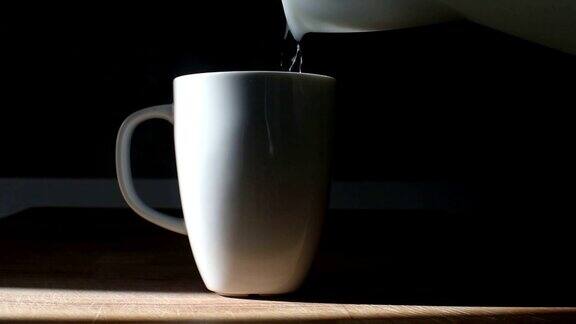 从水壶中倒入滚烫的开水到白咖啡或茶杯中