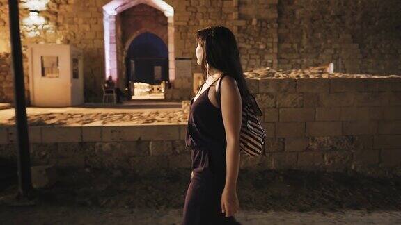 年轻女子走在凯撒利亚老城夜袭黑发女子走在古城废墟中美丽的地方