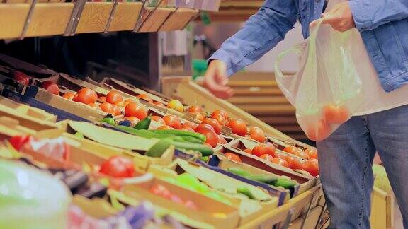 一个男人把西红柿放在商店的包装里在超市买蔬菜特写镜头
