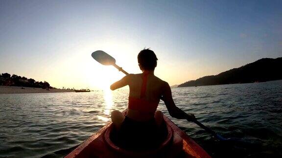 一位女子在日落时分划皮划艇