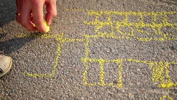 一家人带着孩子在柏油路上用粉笔画画在户外游戏