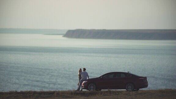这对浪漫的情侣在海边的汽车旁拥抱着