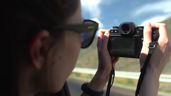 美丽的亚洲女孩在黑色太阳镜的照片与复古相机在公路旅行在敞篷车
