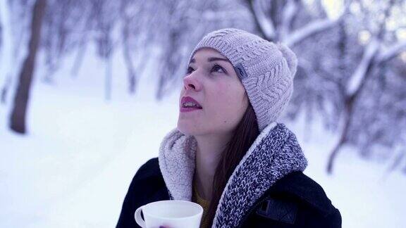 下雪的时候一名穿着针织衣服的年轻女子正在森林里喝茶