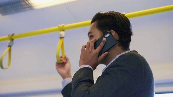 在亚洲冠状病毒爆发期间一名戴着防护口罩的男子在火车上使用手机