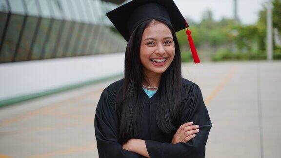 年轻快乐的亚洲少女庆祝她的毕业同时看着镜头和笑