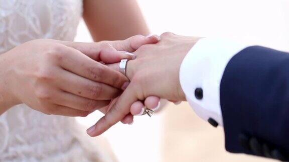 在海滩婚礼上新娘把结婚戒指戴在新郎的手指上