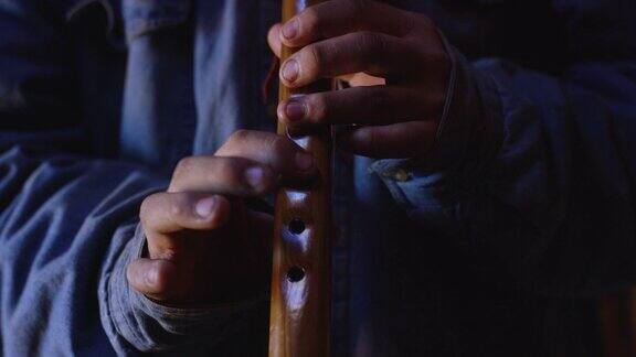 一个十几岁的美国土著男孩在霍根(纳瓦霍小屋)里吹着纳瓦霍长笛