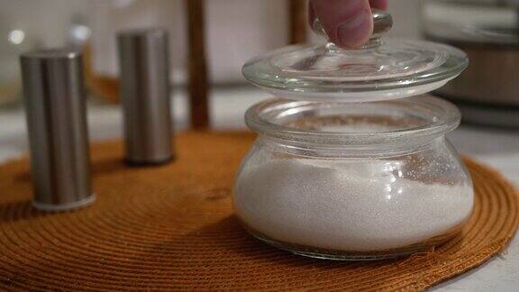 糖碗盐和胡椒瓶用手拿开玻璃糖碗的盖子