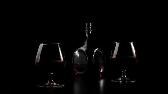 豪华白兰地黑色的桌子上放着两只玻璃杯背景是黑色的一缕光线照在桌子上玻璃在光线下发出眩光闻鼻器里的酒精