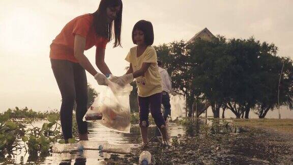亚洲志愿者家庭晚上在河边收集塑料瓶和水葫芦