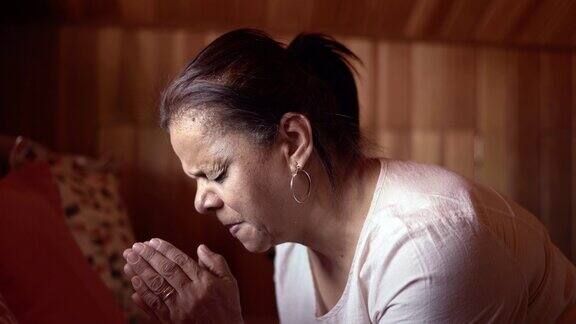 一位年长妇女在家祈祷的侧面图