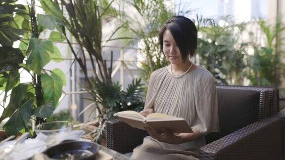 一名日本妇女在户外咖啡馆吃完午饭后看书