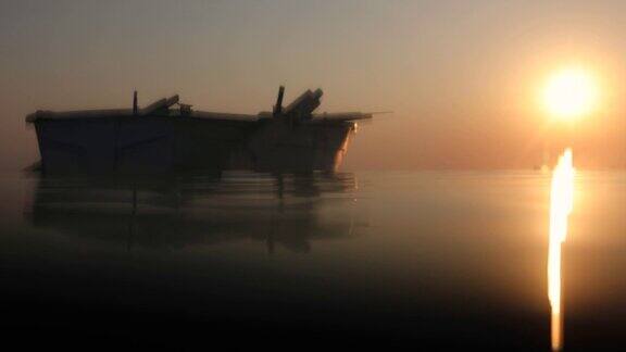 在日落时漂浮在公海上的空的旧木船