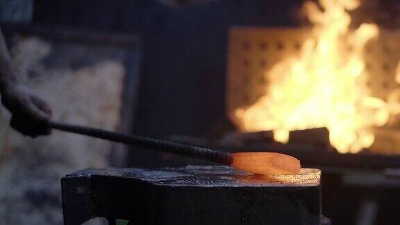 铁匠的手用铁锤敲击白炽的灼热的金属在铁砧上缓慢的锻造过程