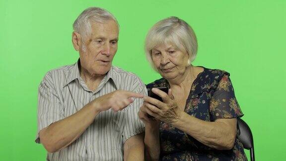 老男人和老女人坐在一起玩智能手机色度键
