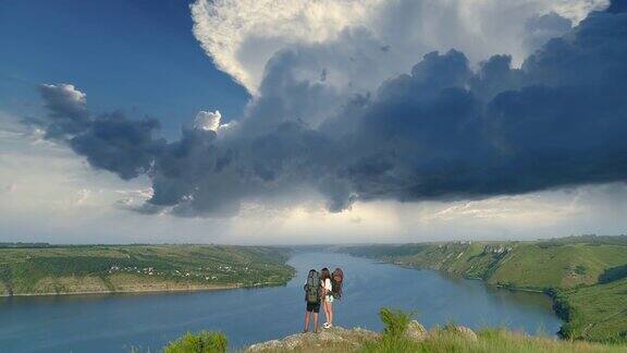 这对年轻夫妇站在山顶上俯瞰着风景秀丽的河流