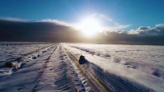 汽车在冰岛路上行驶白雪山脉和日落乡村冬天4K鸟瞰图