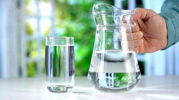 特写从厨房桌子上的水壶中倒出纯净的新鲜饮用水