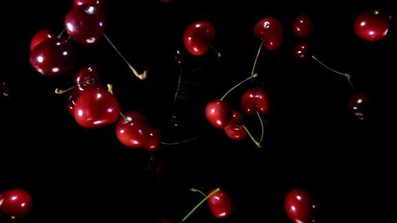 特写美味的红樱桃弹起和旋转在黑色的背景