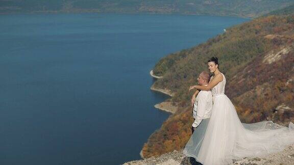 年轻美丽的新婚夫妇一起在海边山上的斜坡上可爱的新郎和新娘慢动作