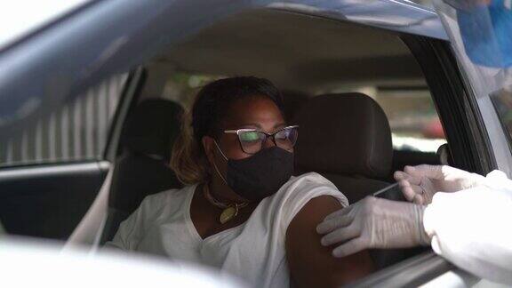 医生穿著防护服在驾车穿过的路上给病人注射疫苗