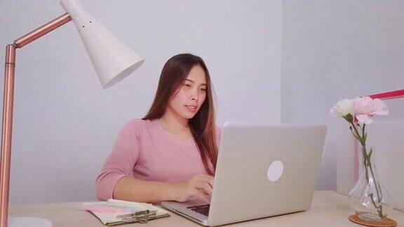 亚洲妇女在家里用笔记本电脑做家庭作业