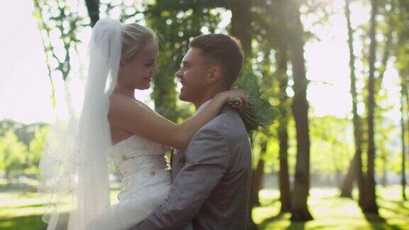 新娘和新郎在一个阳光灿烂的公园里互相拥抱