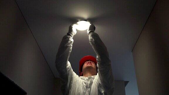 由专业电工将圆形led灯安装在天花板孔内
