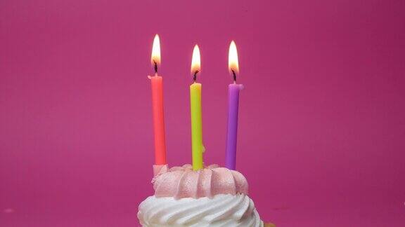 生日纸杯蛋糕与蜡烛和生日装饰在粉红色的背景