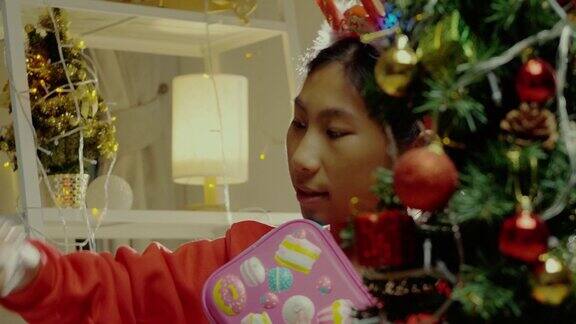 快乐亚洲女孩穿着绿色毛衣和红色发带打开礼物盒与圣诞装饰背景假日概念