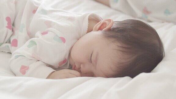 8个月大的女婴在家里白色的床上睡觉的4k视频