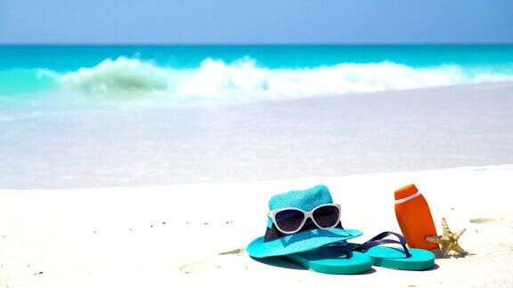 沙滩配饰草帽、人字拖、奶油色瓶子和白色沙滩上的太阳镜