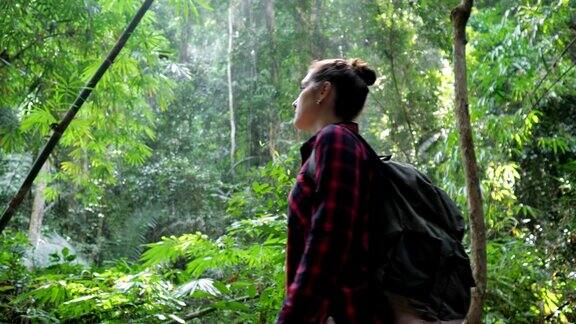 郁郁葱葱的热带雨林和背包女通过相机